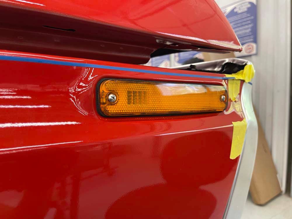 A close up of a red car with a yellow tape on it.