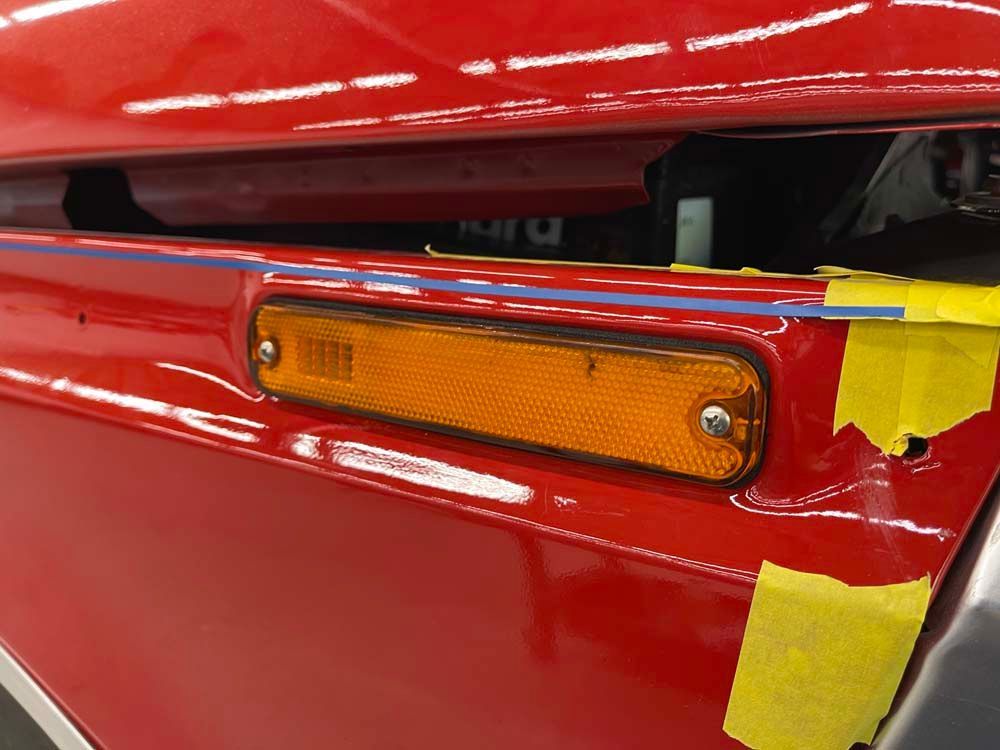 A close up of a red car with yellow tape on it