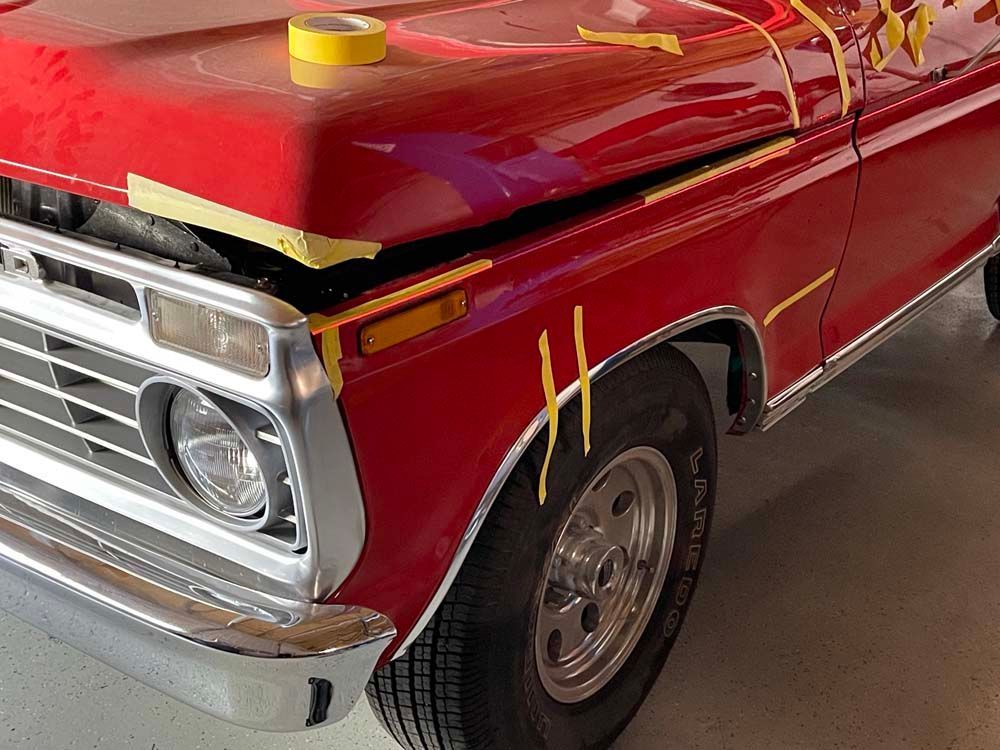A red truck is sitting in a garage with yellow tape on it.
