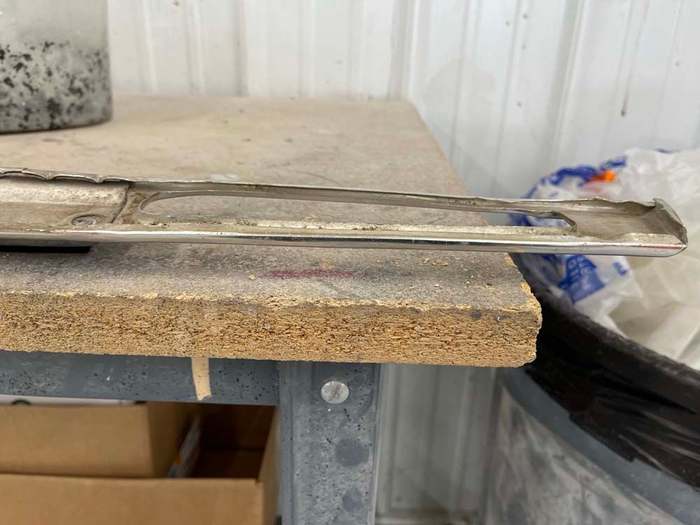 A piece of metal is sitting on top of a wooden table.