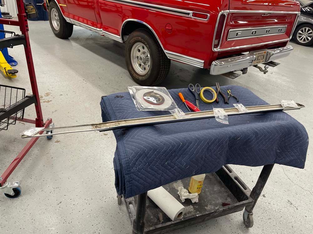 A red truck is parked in a garage next to a table with tools on it.