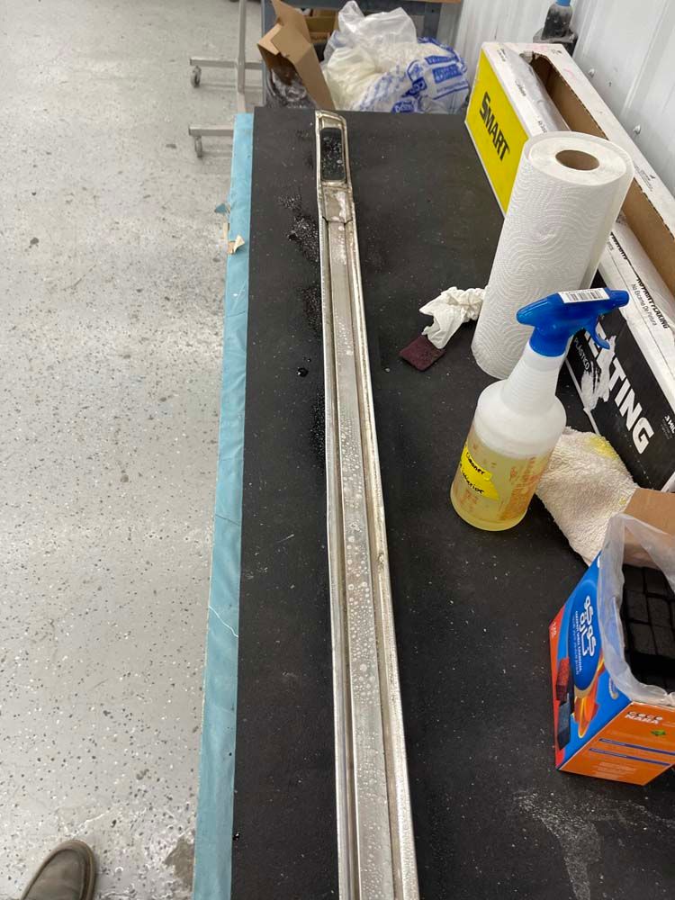 A long piece of metal is sitting on a table next to a spray bottle and paper towels.