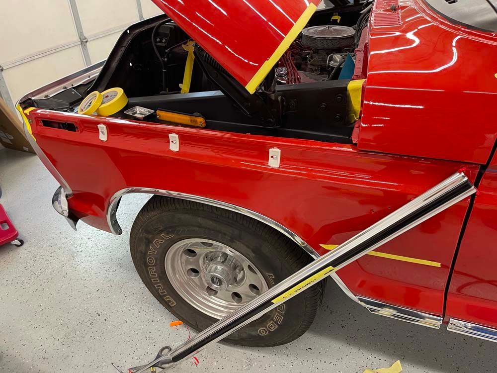 A red truck with the hood up is sitting in a garage.