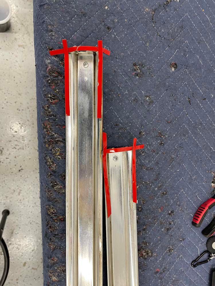 Two metal bars with red tape on them are sitting on a blue carpet.