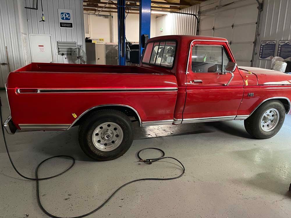 A red truck is parked in a garage next to a lift.