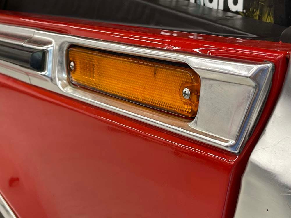 A close up of a red car door with a light on it.