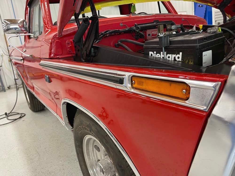 A red truck with the hood up and a diehard battery