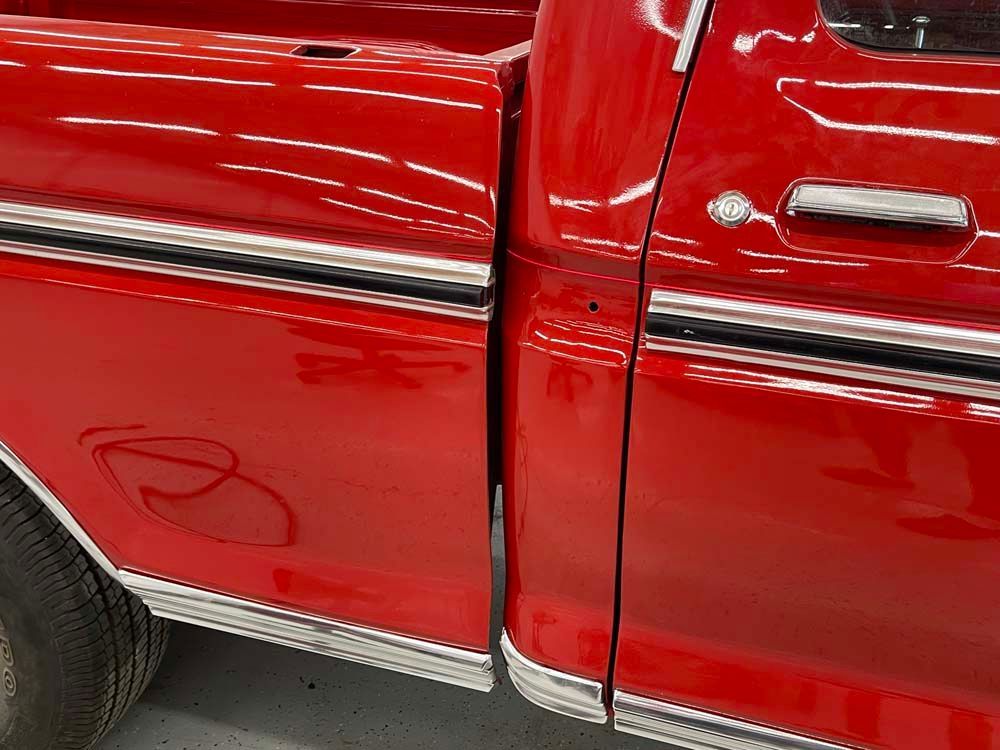 A red truck is parked in a garage with the door open.