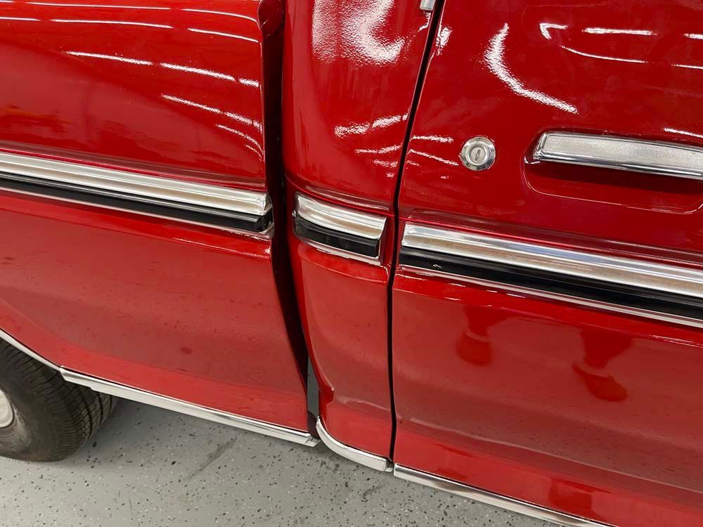 A red truck is parked in a garage with the door open.