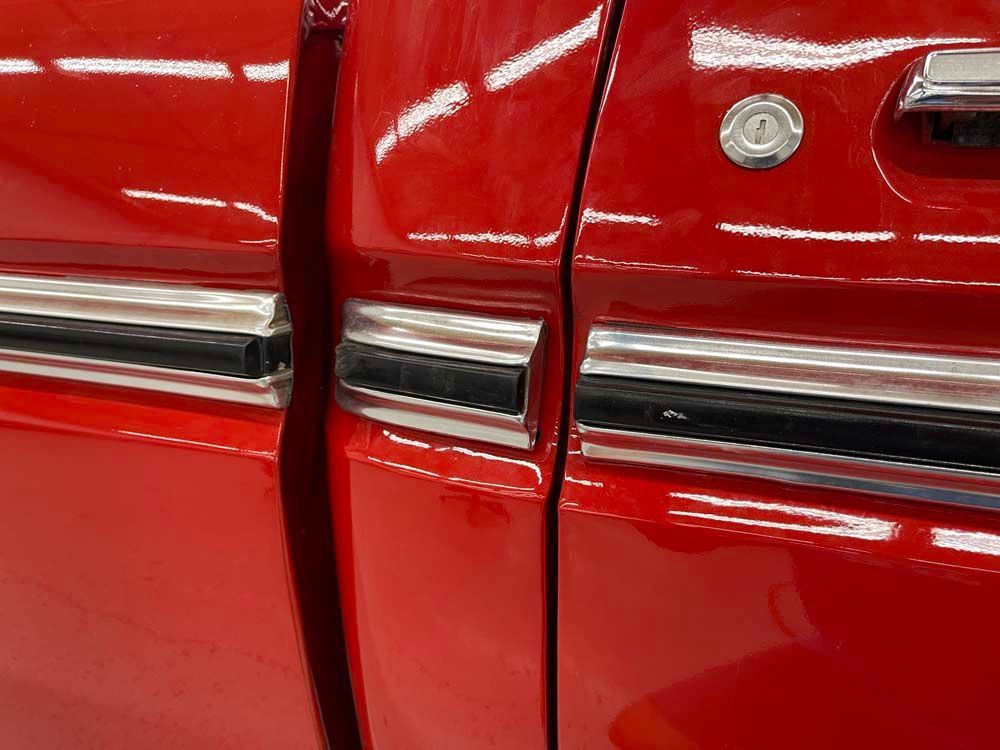 A close up of a red truck door with chrome trim