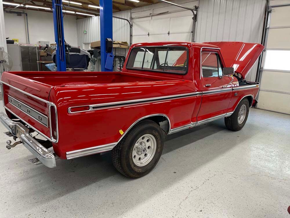 A red truck with the hood up is parked in a garage.
