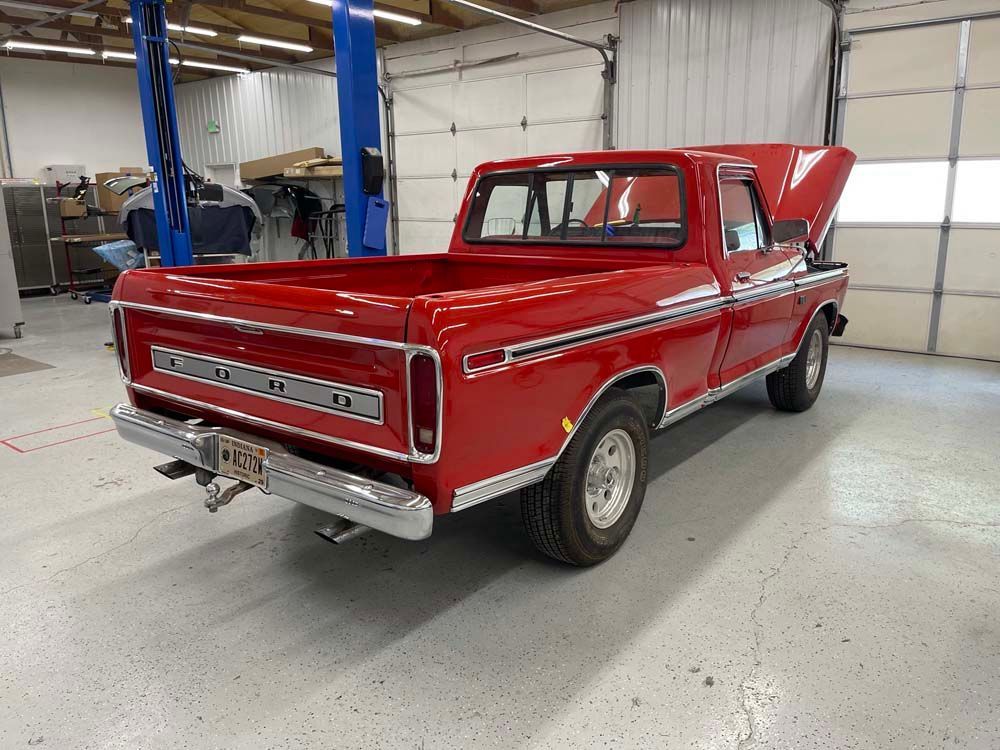 A red truck with the hood up is parked in a garage.