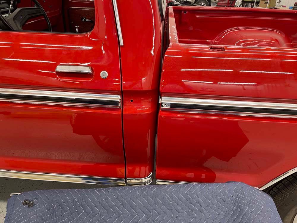 A red truck is parked next to a blue blanket.