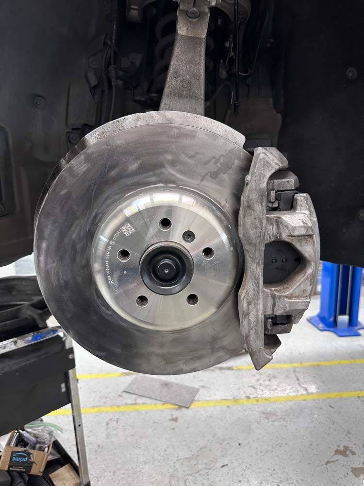 A close up of a brake disc on a car in a garage.