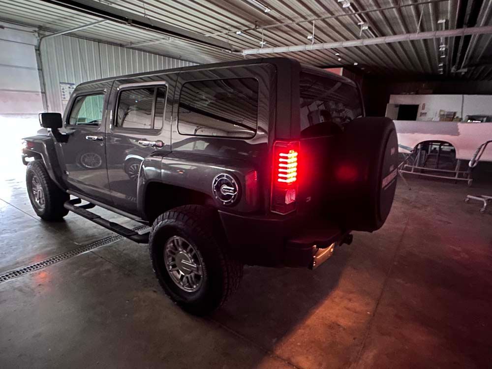 A hummer h3 is parked in a garage with its rear lights on.