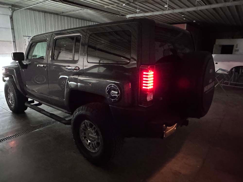 A hummer suv is parked in a garage with its lights on.
