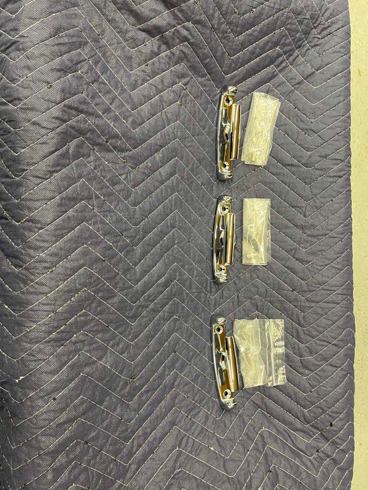 Three metal clips are sitting on top of a blue quilt.