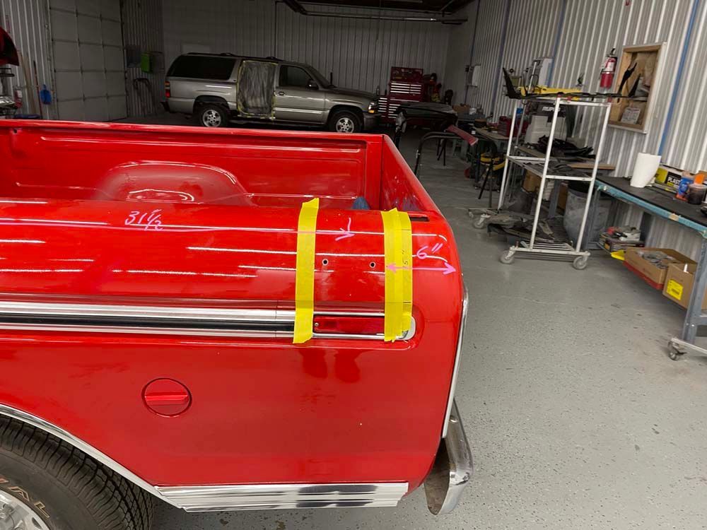 A red truck is sitting in a garage with yellow tape on it.