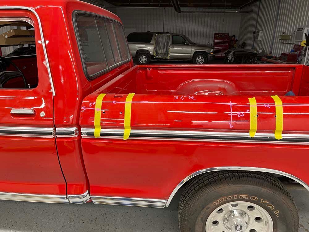 A red truck with yellow tape on the side is parked in a garage.