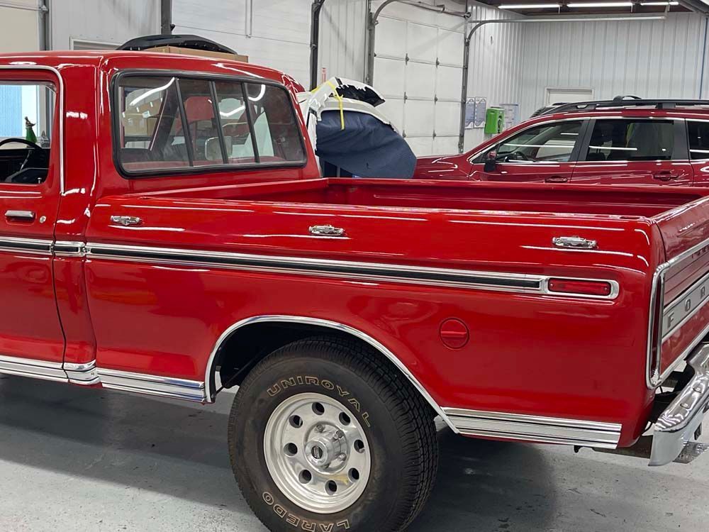 A red truck is parked in a garage next to another truck.