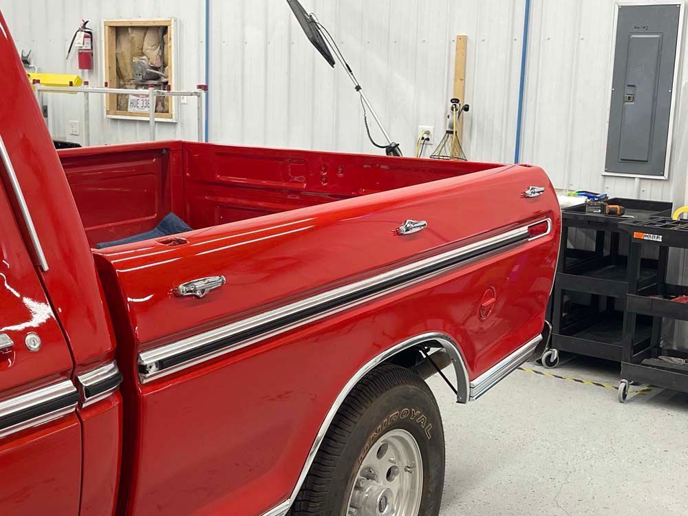 A red truck is parked in a garage with the bed open.