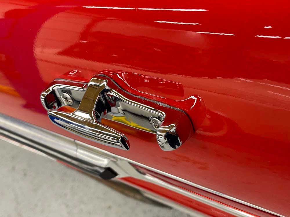 A close up of a red car with a chrome door handle.