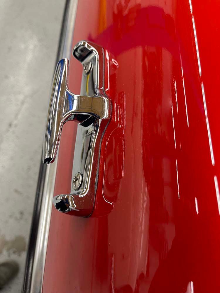 A close up of a chrome handle on a red car