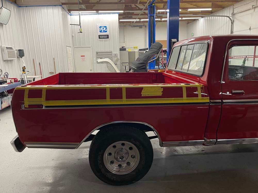 A red truck is sitting on a lift in a garage.