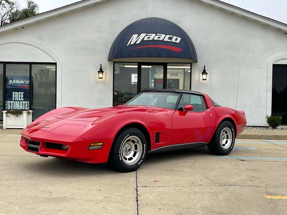 A red corvette is parked in front of a building.