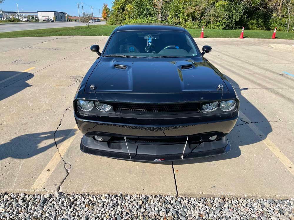 A black dodge challenger is parked in a parking lot.