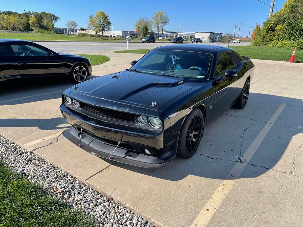 A black dodge challenger is parked in a parking lot.