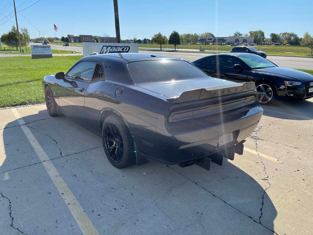 A dodge challenger is parked in a parking lot next to another car.