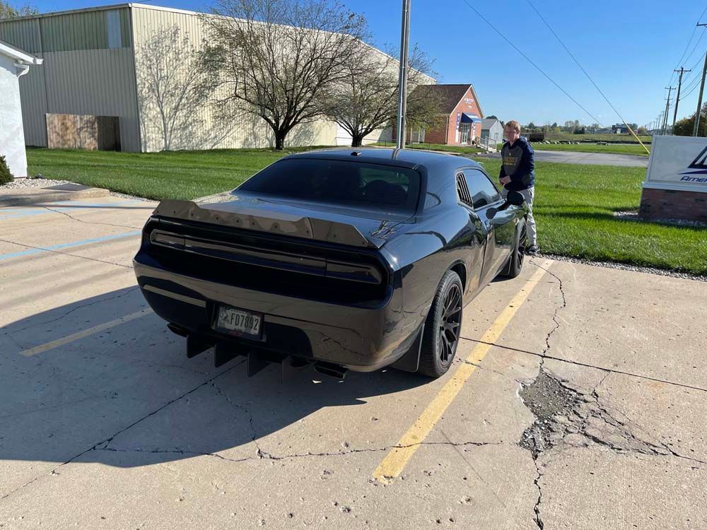 A black dodge challenger is parked in a parking lot.