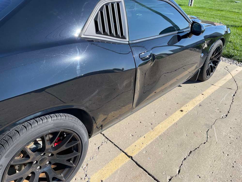 A black dodge challenger is parked in a parking lot.