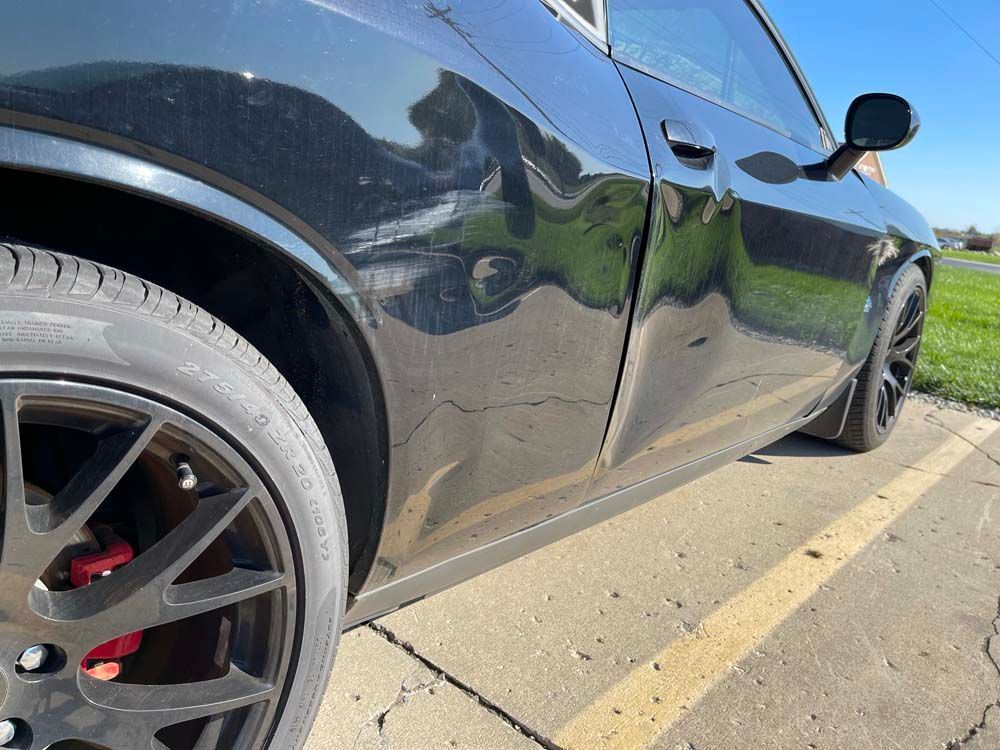 A black dodge challenger is parked in a parking lot.
