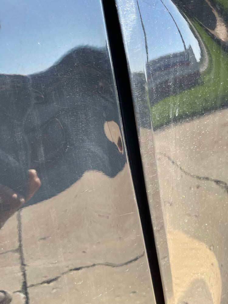 A person is taking a picture of their reflection in a car door.