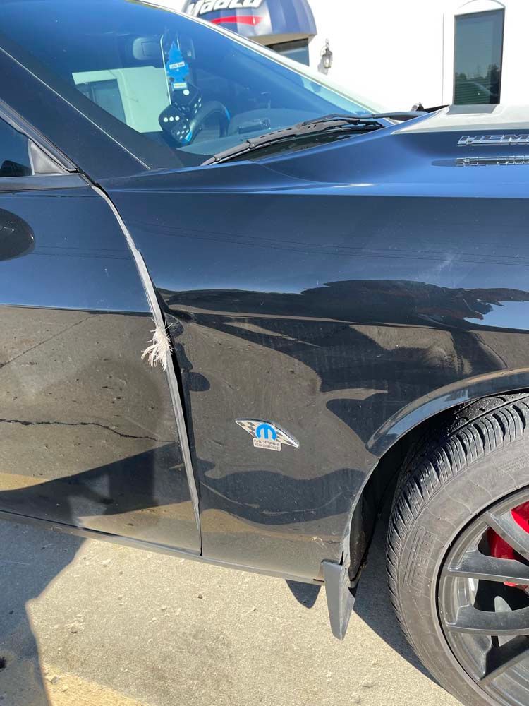 A black dodge challenger is parked in a parking lot.
