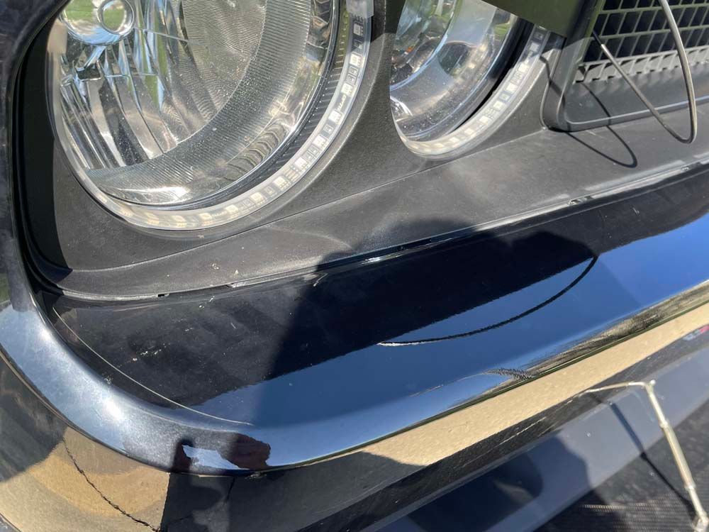 A close up of a black car 's headlight on a sunny day.