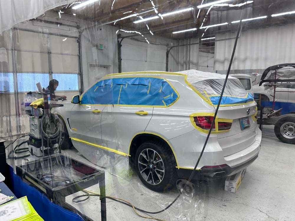 A white car is being painted in a garage.