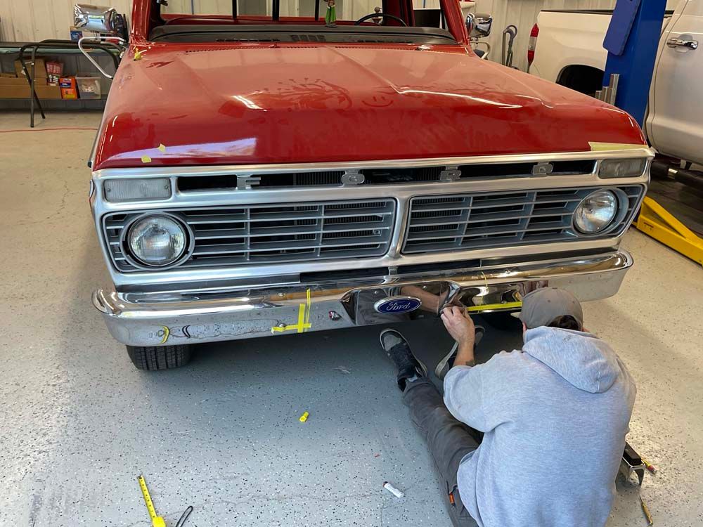 A man is working on a red truck in a garage.