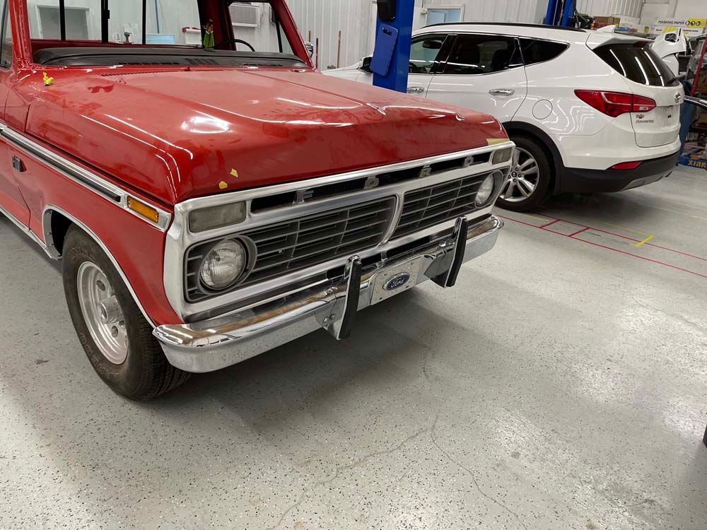A red truck is parked next to a white suv in a garage.