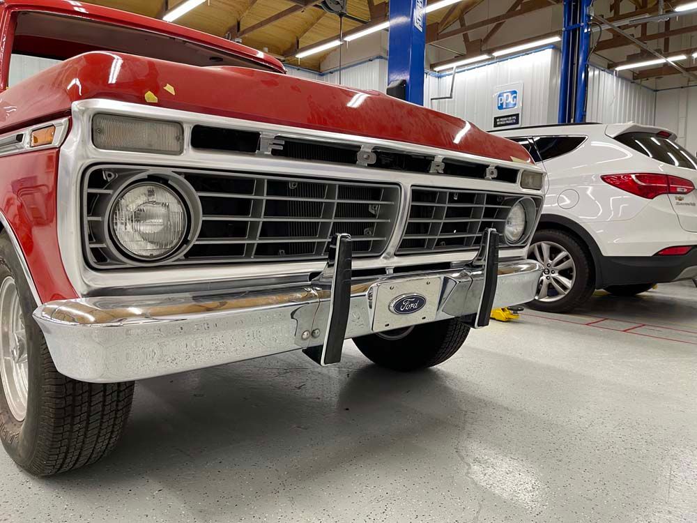 A red ford truck is parked in a garage next to a white suv.