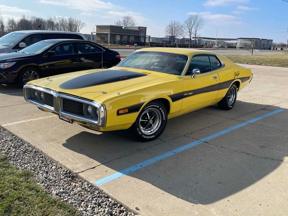 A yellow dodge charger is parked in a parking lot.