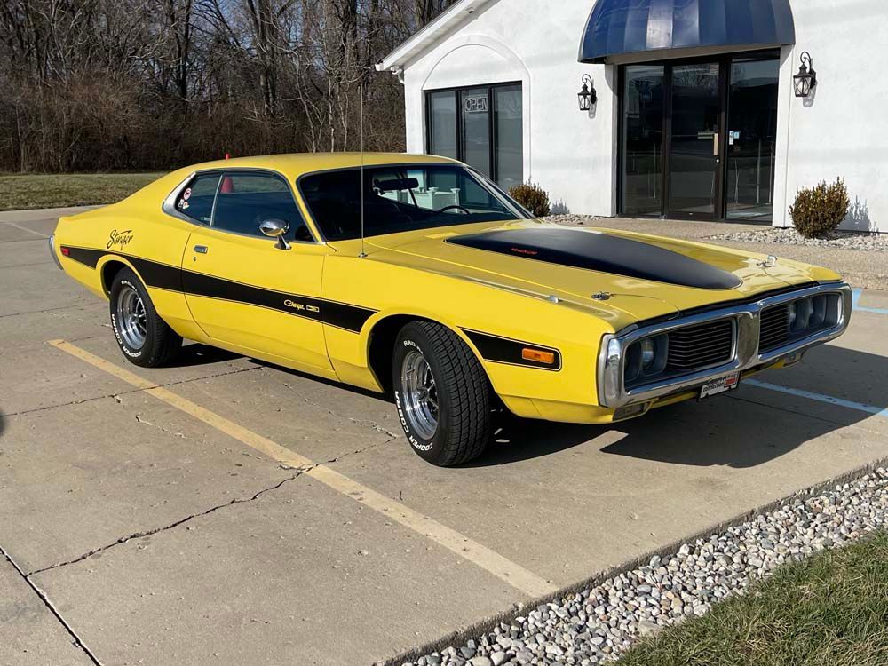 A yellow dodge charger is parked in a parking lot in front of a building.
