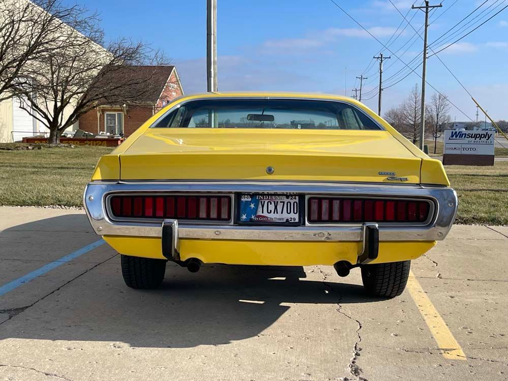 A yellow dodge charger is parked in a parking lot.