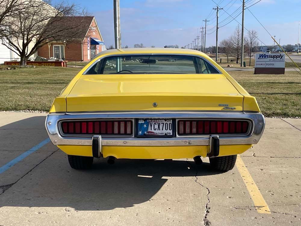 A yellow dodge charger is parked in a parking lot