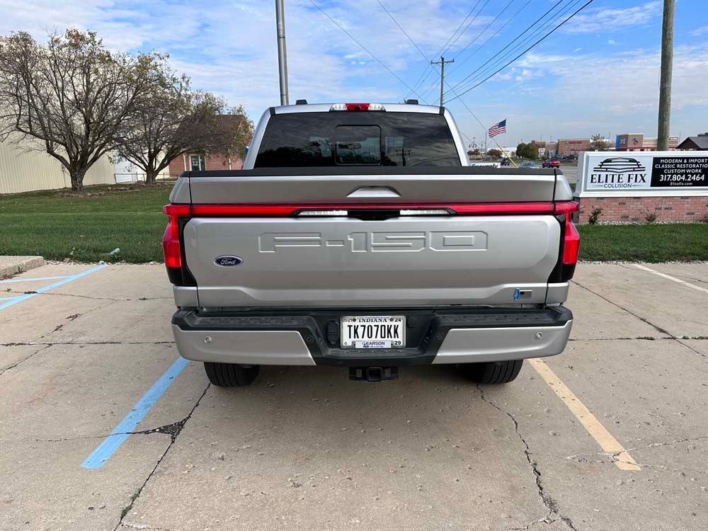 The back of a silver ford f-150 truck is parked in a parking lot.