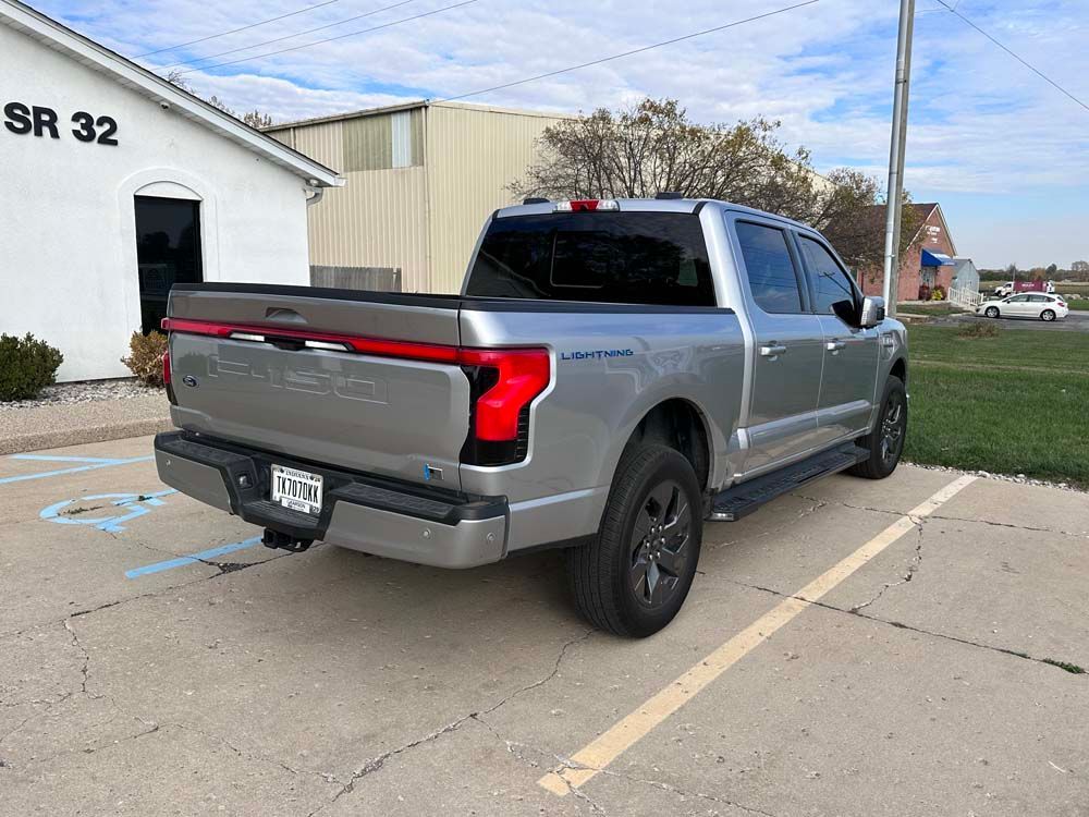 A silver truck is parked in a parking lot in front of a building.