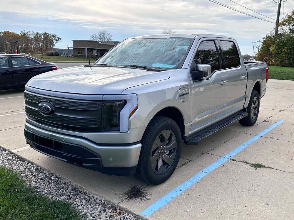 A silver ford f150 lightning pickup truck is parked in a parking lot.