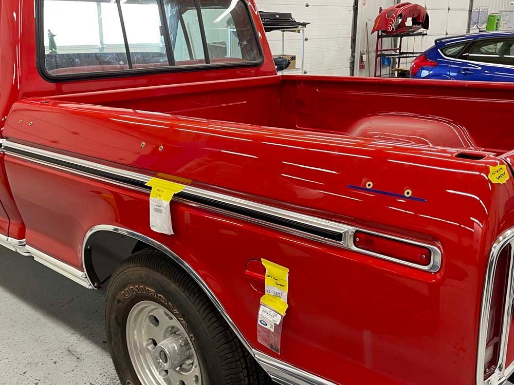 A red truck with a yellow tag on the side is parked in a garage.